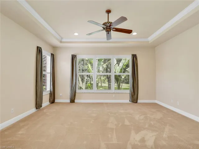 Empty room with plenty of natural light, a raised ceiling, light carpet, recessed lighting, and crown molding