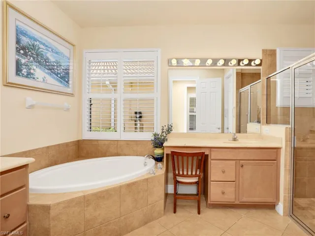 Full bathroom featuring vanity, a shower stall, a garden tub, and light tile patterned flooring