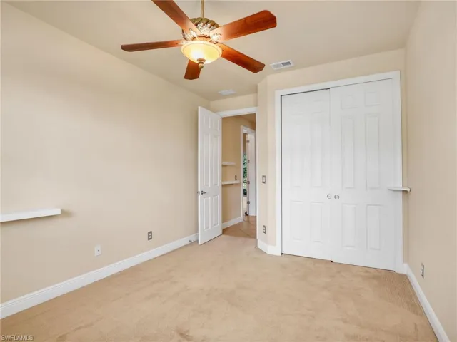 Unfurnished bedroom featuring light colored carpet, ceiling fan, and a closet