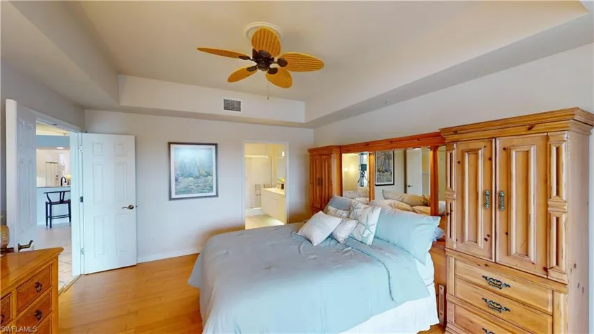 Bedroom featuring ensuite bathroom, ceiling fan, and light wood-type flooring