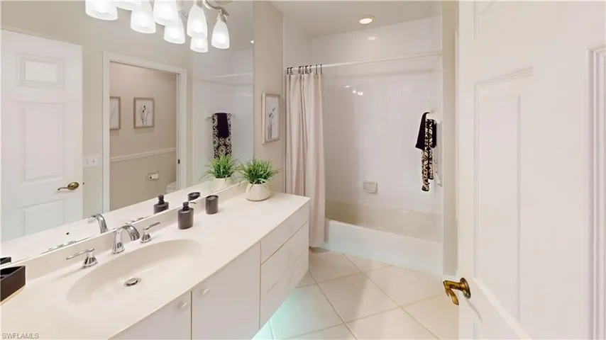 Full bathroom featuring toilet, vanity, shower / bath combo with shower curtain, and tile patterned flooring