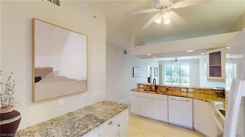 Kitchen featuring white cabinetry, sink, light stone countertops, light tile patterned floors, and white appliances