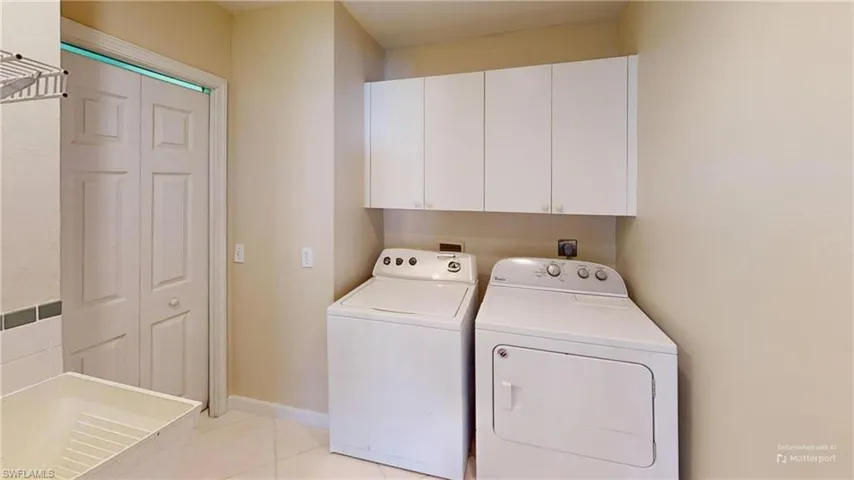 Clothes washing area featuring cabinets, light tile patterned floors, and washer and dryer