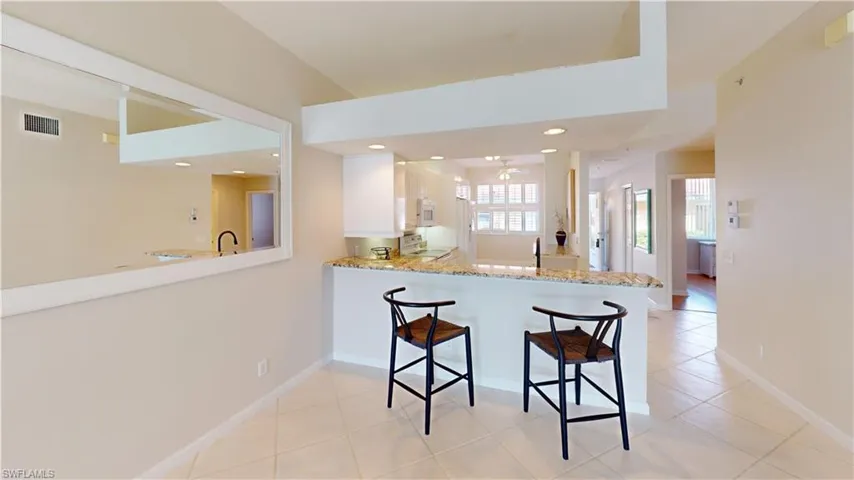 Kitchen featuring a breakfast bar, light stone counters, kitchen peninsula, range, and white cabinets