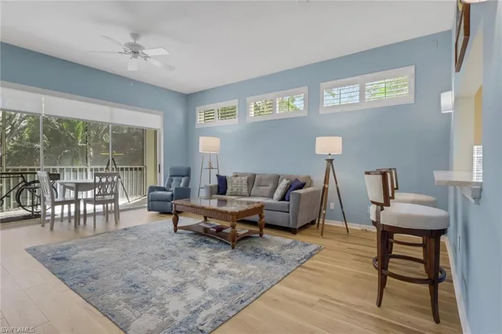 Living area with ceiling fan, light wood-style flooring, and a sunroom