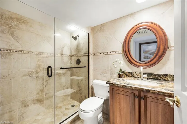 Full bathroom featuring vanity, tile walls, and a shower stall