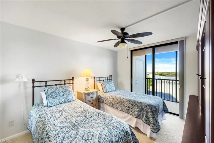 Bedroom featuring twin beds, sliders to lanai and light colored carpet, ceiling fan, access to outside, a water view, and floor to ceiling windows