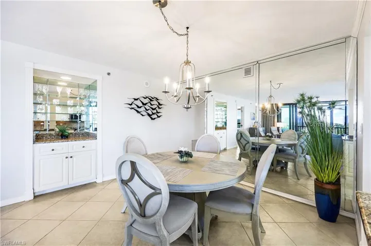 Mirrored Bar and Dining room with light tile patterned floors and a chandelier