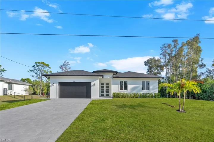 Prairie-style home with stucco siding, an attached garage, and decorative driveway