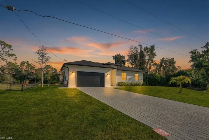 View of front of house with a garage, decorative driveway, and stucco siding