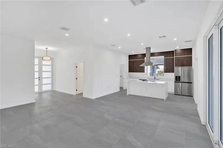 Kitchen featuring dark brown cabinets, modern cabinets, open floor plan, a kitchen island, and stainless steel fridge with ice dispenser