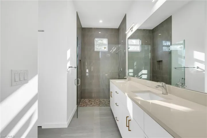 Full bath featuring double vanity and a stall shower