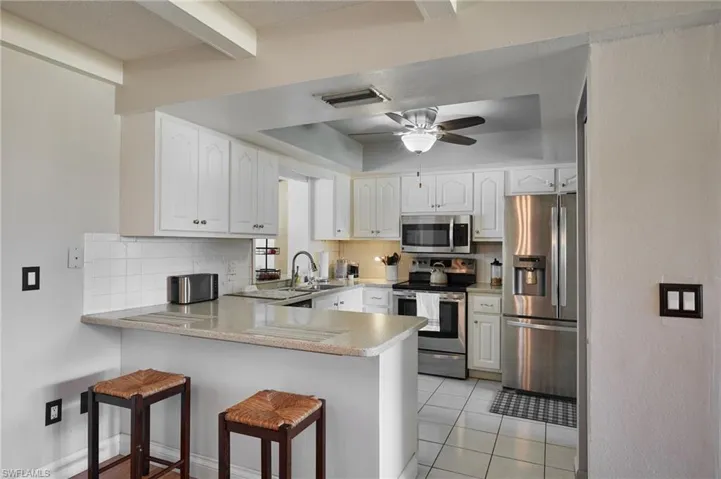 Kitchen featuring backsplash, appliances with stainless steel finishes, a peninsula, and a sink