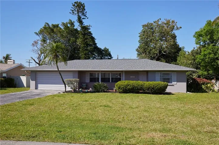 Ranch-style home with fence, a front yard, stucco siding, a garage, and driveway