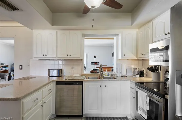 Kitchen with visible vents, ceiling fan, a peninsula, stainless steel appliances, and a sink