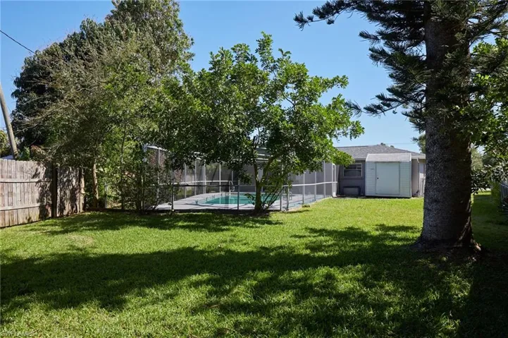 View of yard with glass enclosure, a fenced backyard, and a fenced in pool