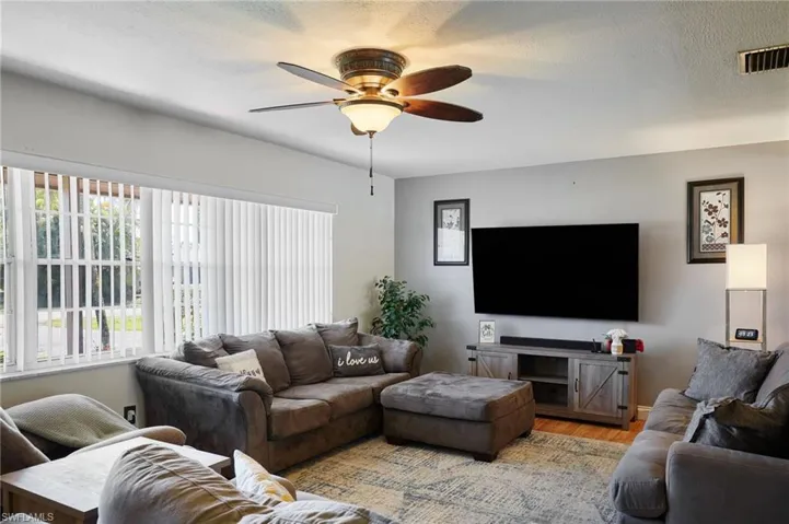 Living room with visible vents, plenty of natural light, light wood-type flooring, and ceiling fan