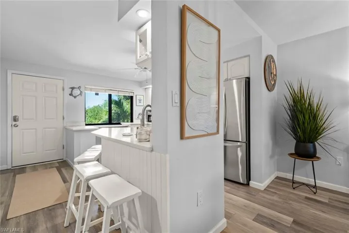Kitchen featuring a breakfast bar with stone-finish countertop, wood-finish flooring, recessed lighting, and stainless steel refrigerator