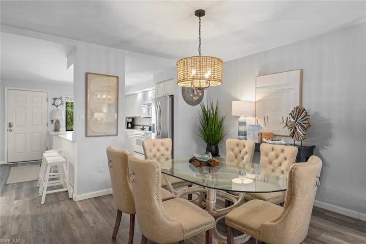 Dining area featuring wood-finish flooring, a neutral color palette, and a textured drum pendant light fixture