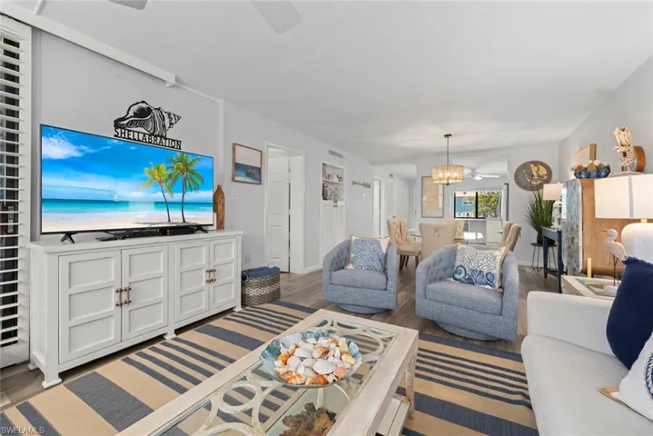 Living space featuring wood-finish flooring, white built-in cabinetry, and a tiered glass chandelier