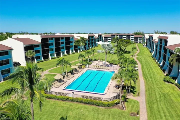 Community swimming pool featuring a paved deck and manicured grounds with mature palm trees and brick pathways