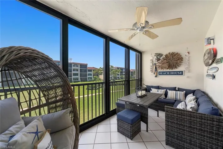 Enclosed balcony featuring tile flooring, floor-to-ceiling glass sliding panels, and a ceiling fan
