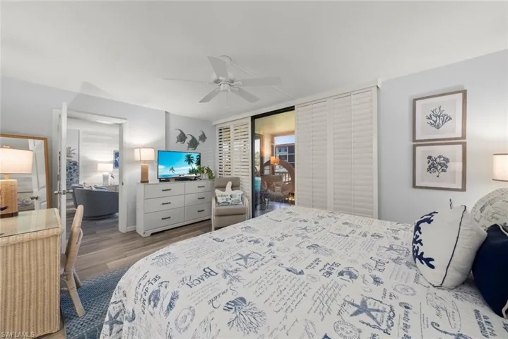 Wood-finish flooring, white ceiling fan, and plantation shutter sliding doors