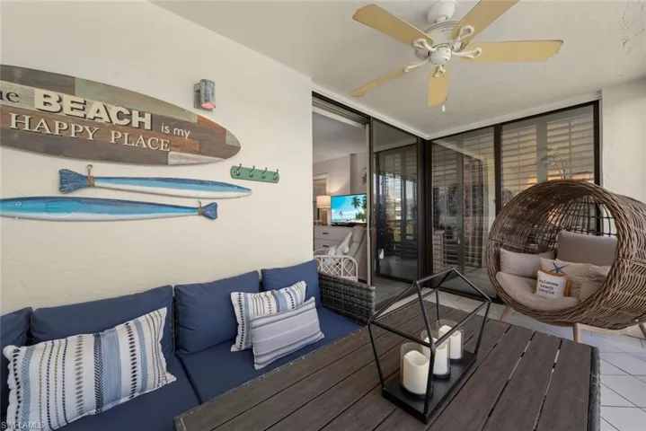 Covered balcony featuring tile flooring, a mounted ceiling fan, and sliding glass door access