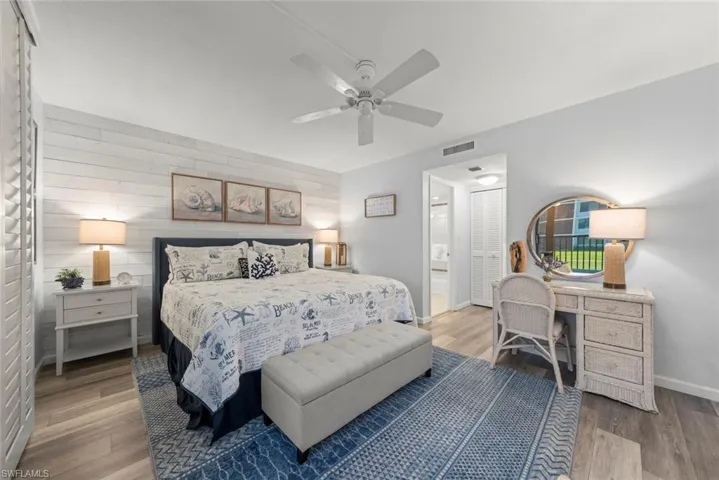 Bedroom featuring wood-finish plank flooring, horizontal shiplap wall accent, and ceiling fan