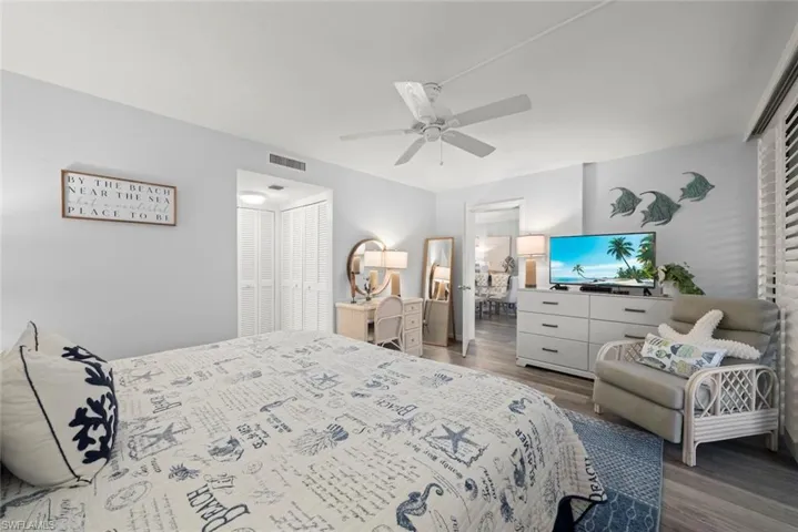 Wood-finish flooring, white ceiling fan, and louvered closet doors