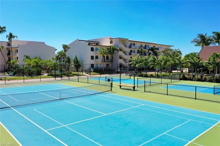 Multi-court hard surface tennis complex with professional-grade perimeter fencing and built-in bench seating