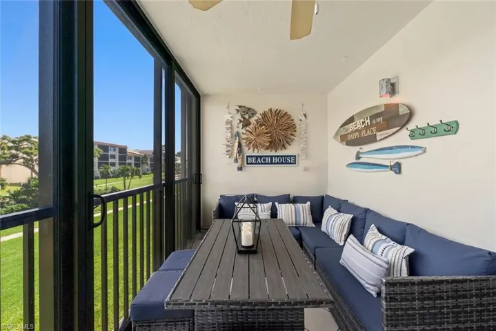Screened-in balcony featuring black metal railings, a ceiling fan, and exterior wall-mounted lighting