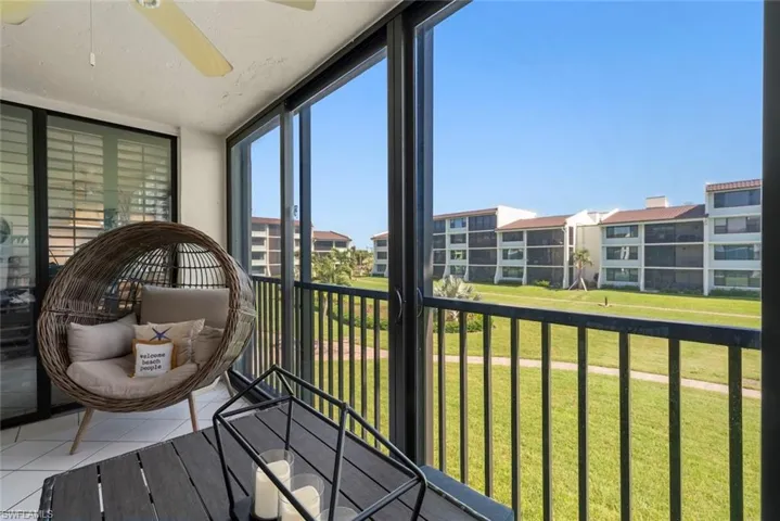 Enclosed balcony featuring tile flooring, ceiling fan, black metal railings, and sliding glass panel doors