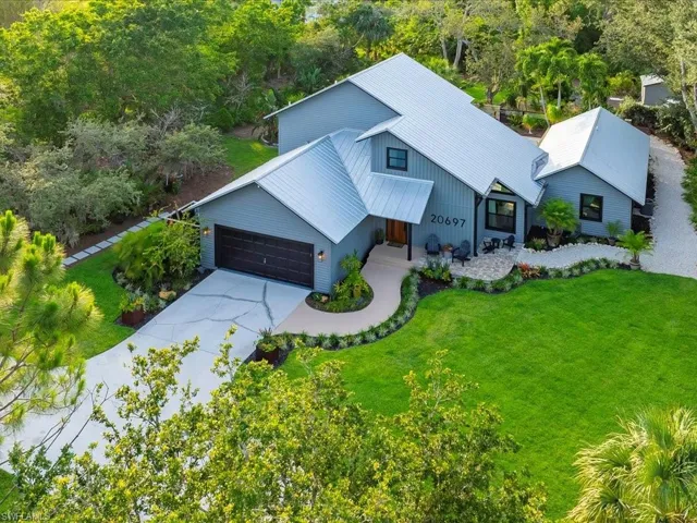View of front of home featuring an attached garage, concrete driveway, a front lawn, metal roof