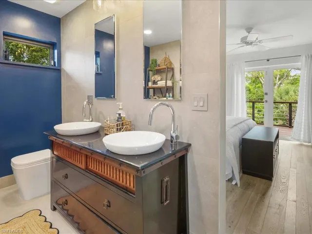 Primary bathroom featuring healthy amount of natural light, ceiling fan, finished floors, and double vanity