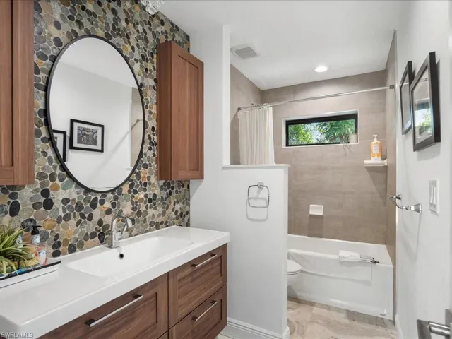 Full bath featuring tasteful backsplash and cabinetry, shower / bathtub combination