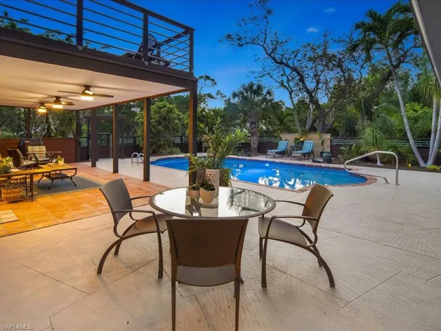View of swimming pool featuring a patio area, ceiling fan, fence, and outdoor dining space