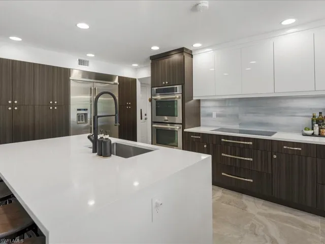 Kitchen with stainless steel appliances, modern cabinets, white cabinetry, dark brown cabinets, and recessed lighting