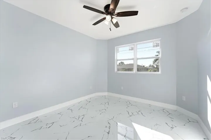 Empty room featuring marble finish floors and a ceiling fan