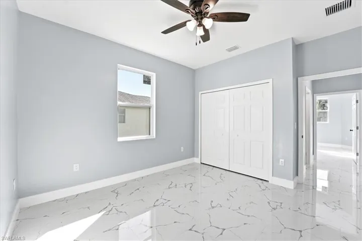 Unfurnished bedroom featuring light marble finish floors, a closet, and ceiling fan