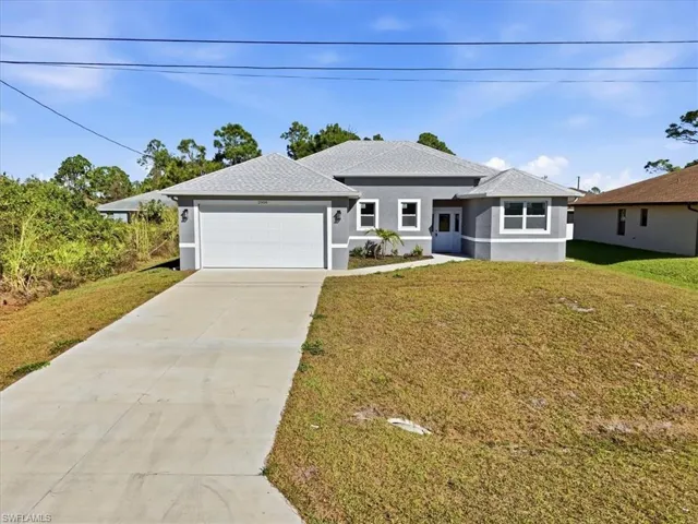 View of front of property with driveway, stucco siding, and a front yard