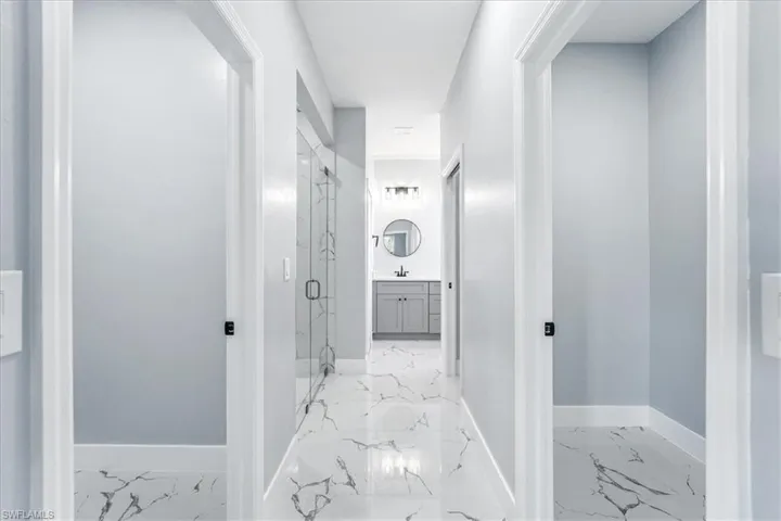 Hallway with baseboards and light marble finish floors