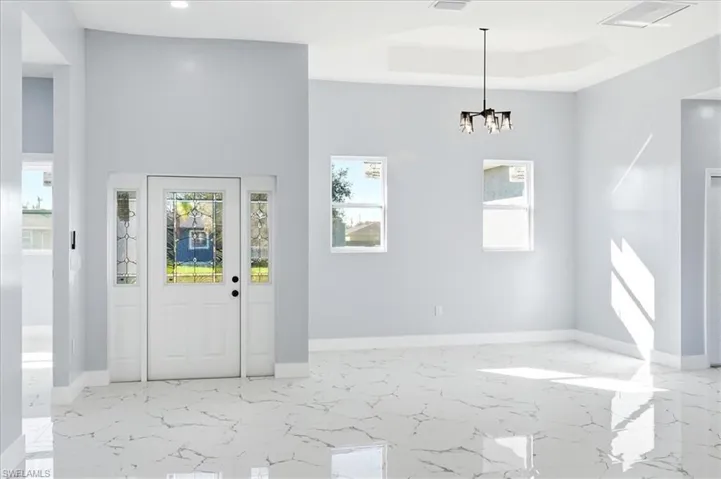 Entryway featuring light marble finish floors and a raised ceiling