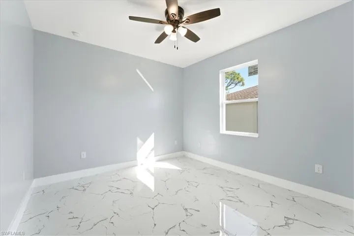 Empty room with marble look tile flooring and ceiling fan
