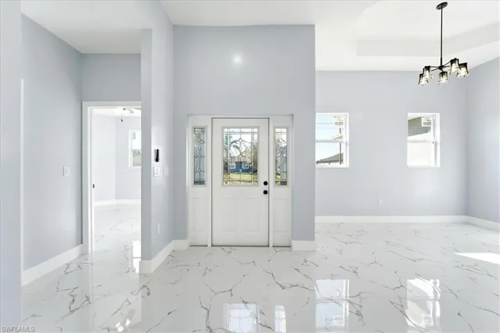 Foyer featuring light marble finish flooring and a chandelier