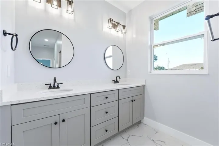 Bathroom with light marble finish floors and double vanity