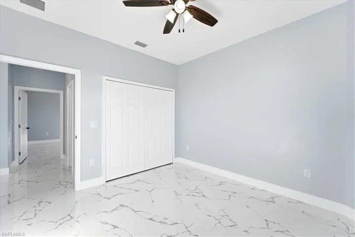 Unfurnished bedroom with light marble finish flooring, a closet, and a ceiling fan