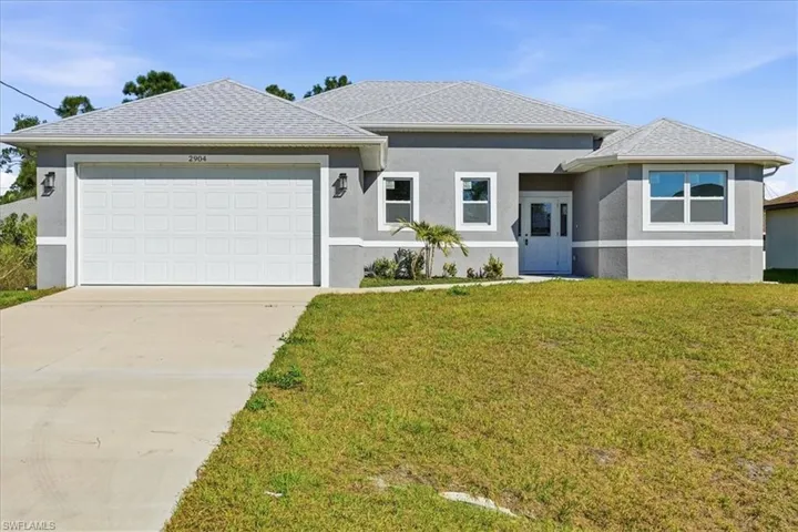 View of front of home featuring stucco siding, a front lawn, and driveway