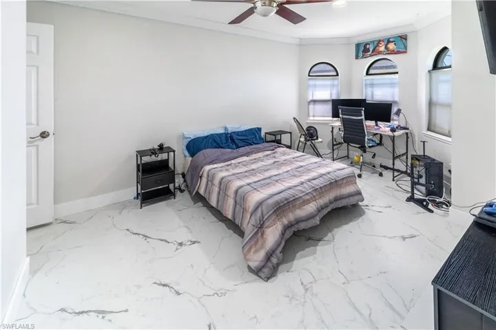 Bedroom with an office area, crown molding, and a ceiling fan