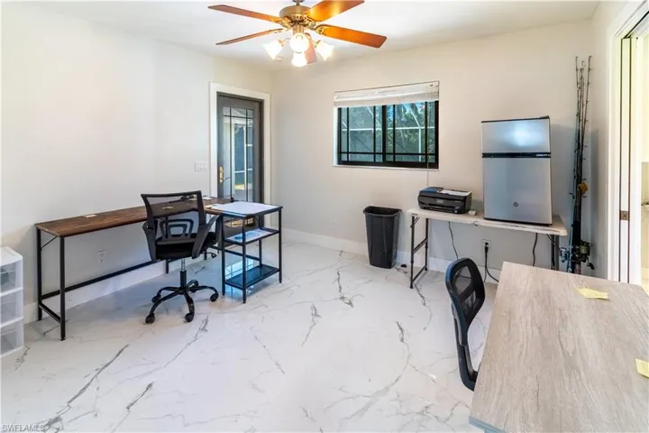 Office area featuring a ceiling fan and light marble finish floors